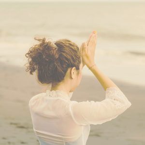 Una mujer de espaldas con las manos en oración en la frente
